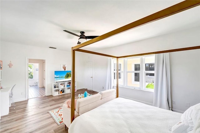 bedroom with ceiling fan, visible vents, baseboards, and wood finished floors