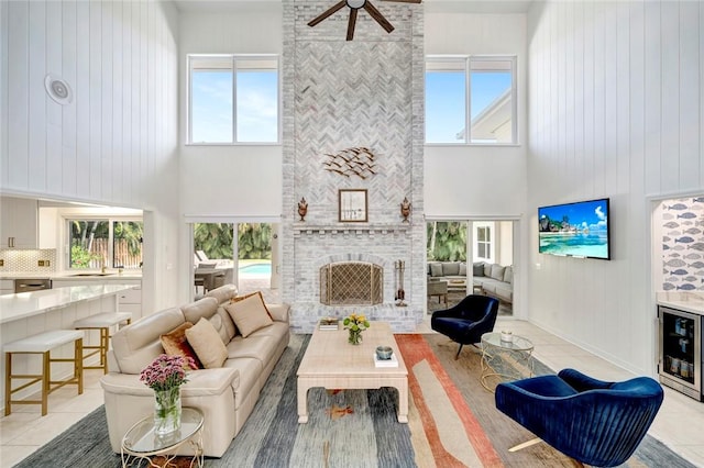 living room with wine cooler, light tile patterned flooring, a fireplace, and a healthy amount of sunlight