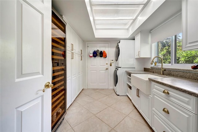 laundry room featuring light tile patterned floors, beverage cooler, cabinet space, a sink, and stacked washer / drying machine