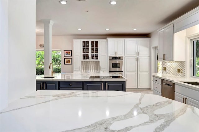 kitchen featuring a sink, stainless steel appliances, light stone counters, and white cabinets