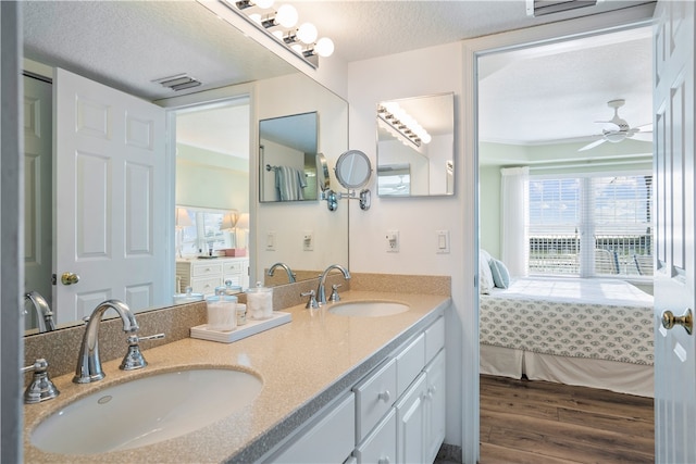 bathroom with vanity, wood-type flooring, ceiling fan, and a textured ceiling