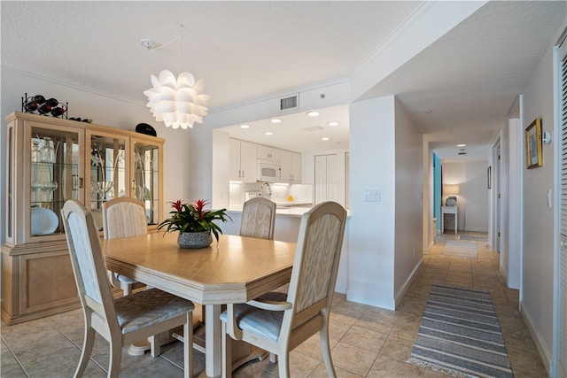 tiled dining room featuring a chandelier, a textured ceiling, and ornamental molding