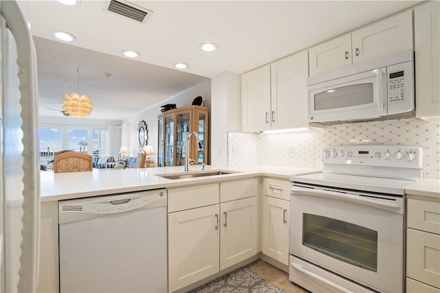 kitchen with white cabinetry, white appliances, decorative backsplash, sink, and kitchen peninsula