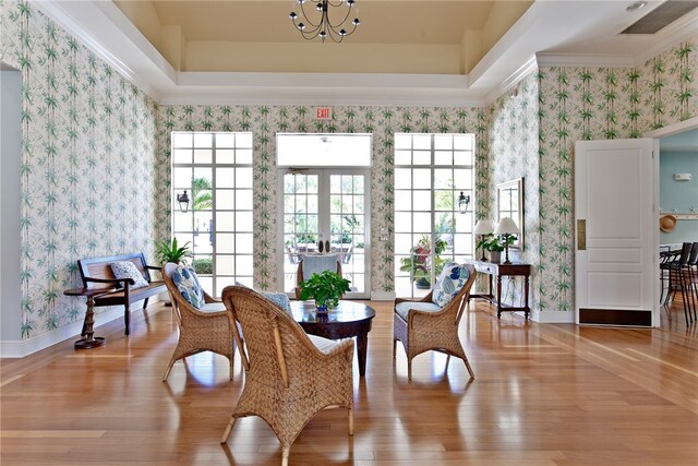 sitting room featuring crown molding, light hardwood / wood-style flooring, and a raised ceiling