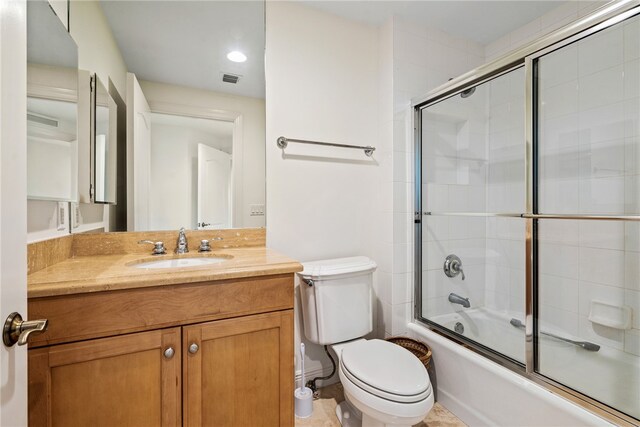 full bathroom with bath / shower combo with glass door, vanity, and toilet