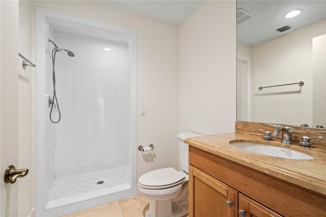 bathroom featuring toilet, vanity, tile patterned floors, and a tile shower