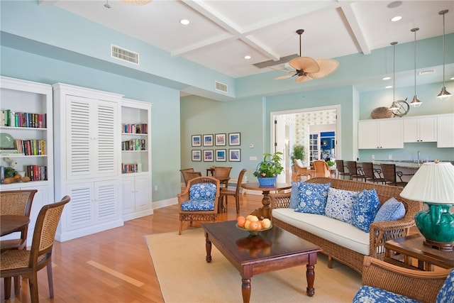 living area featuring light hardwood / wood-style flooring, ceiling fan, beam ceiling, and coffered ceiling