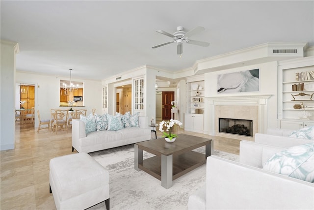 living room featuring built in shelves, crown molding, and ceiling fan with notable chandelier