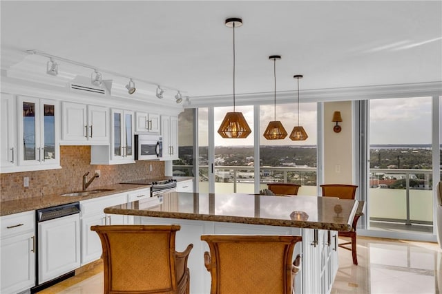 kitchen featuring sink, appliances with stainless steel finishes, white cabinetry, a kitchen breakfast bar, and a kitchen island