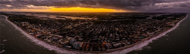 aerial view at dusk with a water view and a view of the beach