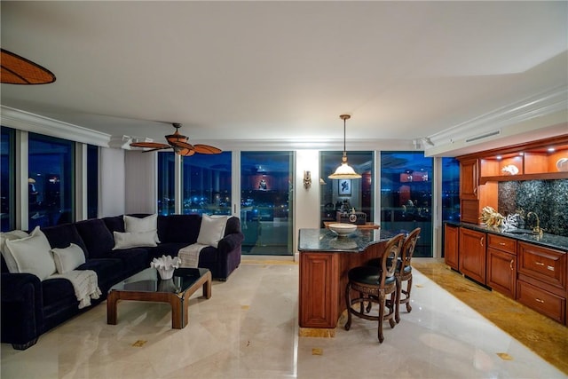 interior space with decorative light fixtures, sink, dark stone counters, ornamental molding, and ceiling fan