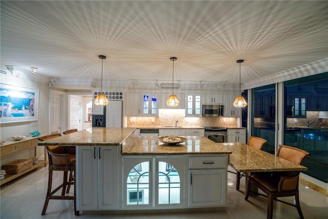 kitchen with a spacious island, light stone counters, decorative light fixtures, appliances with stainless steel finishes, and backsplash