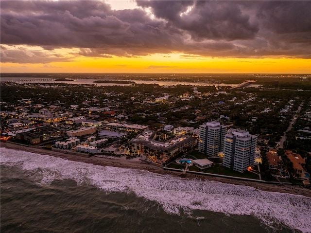 aerial view at dusk with a beach view and a water view