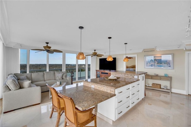 kitchen with dark stone countertops, a breakfast bar area, white cabinets, hanging light fixtures, and a large island