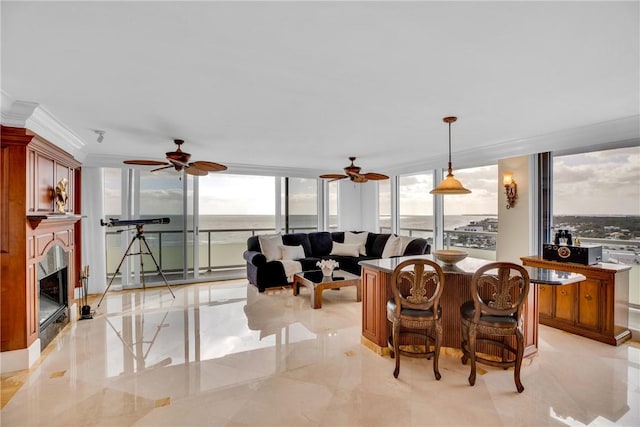 living room featuring ceiling fan, plenty of natural light, a wall of windows, and a water view