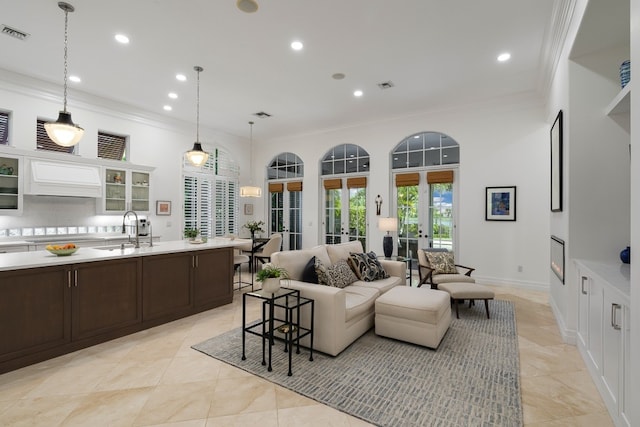 living room with crown molding, light tile patterned floors, sink, and french doors