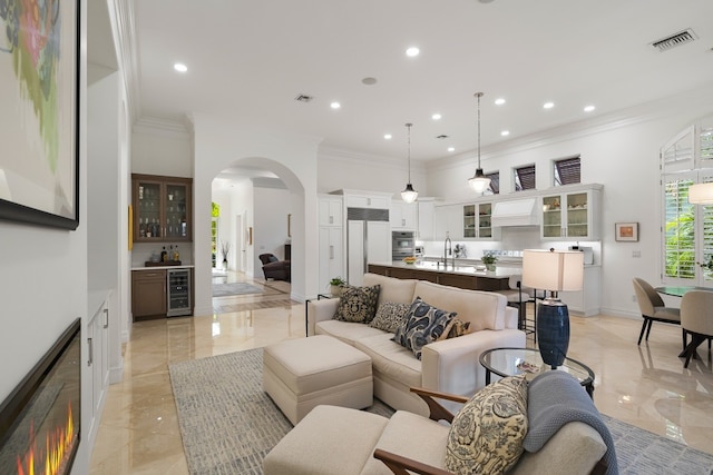 living room with wine cooler, crown molding, and bar