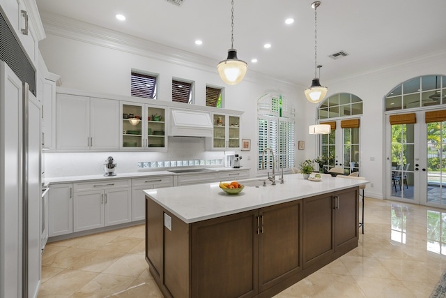 kitchen with french doors, stovetop, sink, ornamental molding, and white cabinets