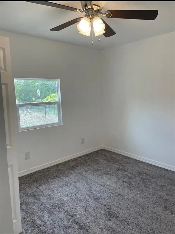 spare room featuring ceiling fan and dark carpet