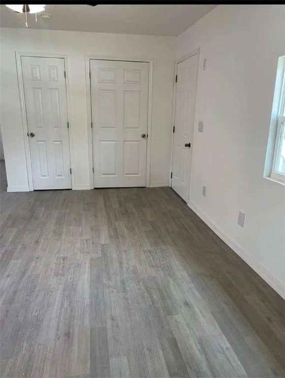 unfurnished bedroom with hardwood / wood-style flooring, ceiling fan, and two closets