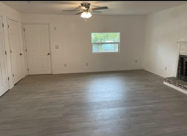 unfurnished living room featuring dark wood-type flooring and ceiling fan