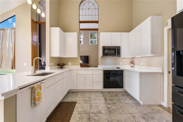 420 Sopwith Dr, Vero Beach, FL 32968 - kitchen featuring black appliances, a sink, a towering ceiling, white cabinetry, and light countertops
