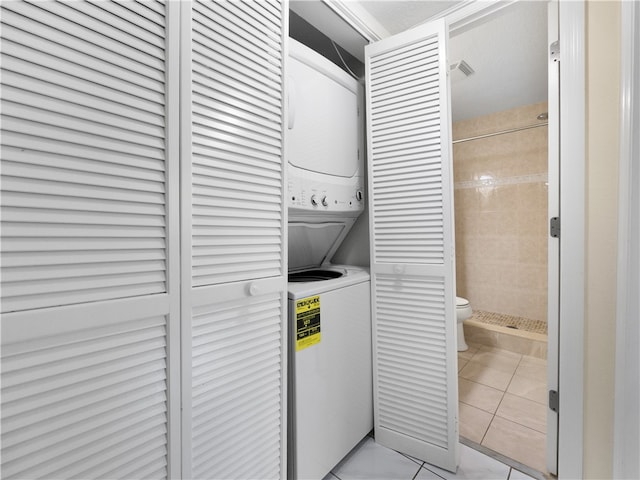 laundry area featuring light tile patterned floors and stacked washer and dryer