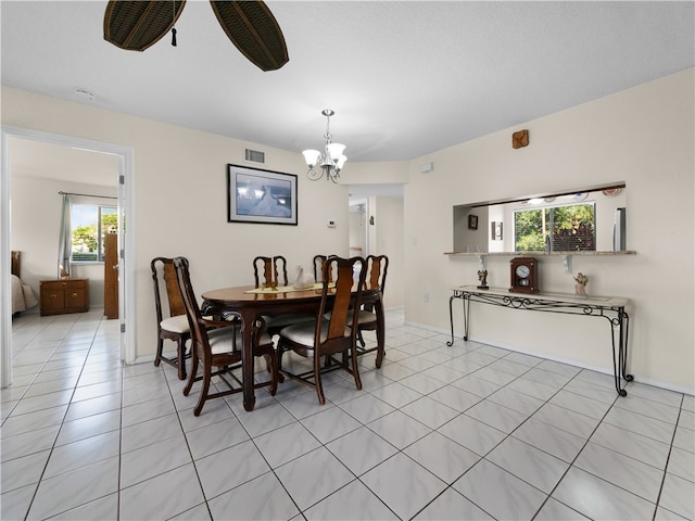 tiled dining room with ceiling fan with notable chandelier