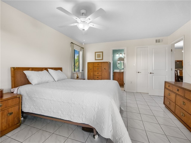 bedroom featuring a closet, light tile patterned flooring, ceiling fan, and ensuite bath