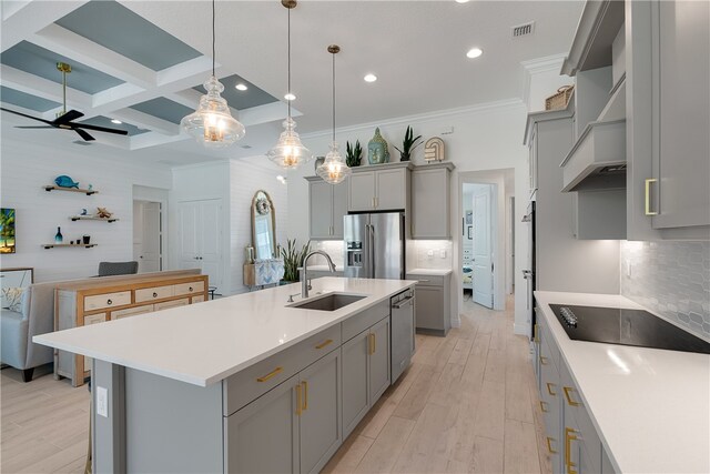 kitchen featuring coffered ceiling, an island with sink, appliances with stainless steel finishes, pendant lighting, and sink