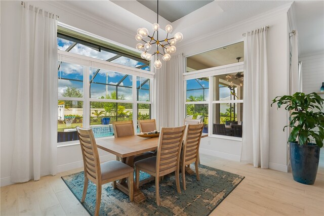 dining space featuring plenty of natural light, light wood-type flooring, a raised ceiling, and an inviting chandelier