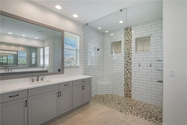 bathroom featuring tile patterned floors, tiled shower, and vanity