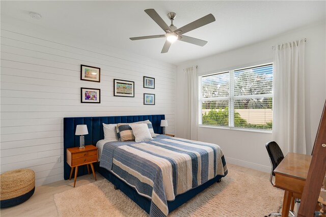 bedroom with ceiling fan and wood walls