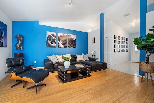 living room with light wood-type flooring, track lighting, and vaulted ceiling