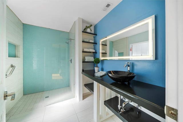 bathroom featuring tile patterned flooring, vanity, and tiled shower