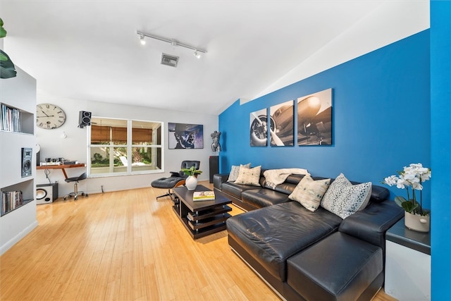 living room with track lighting, lofted ceiling, and hardwood / wood-style flooring