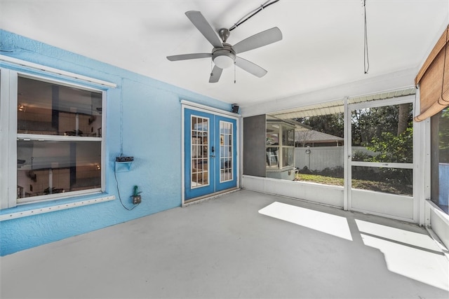 unfurnished sunroom featuring ceiling fan and french doors