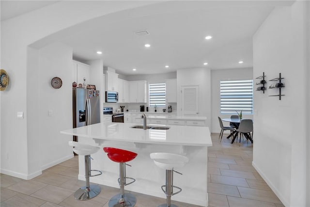 102 52nd Sq, Vero Beach, FL 32967 - kitchen with baseboards, a breakfast bar, an island with sink, stainless steel appliances, and a sink