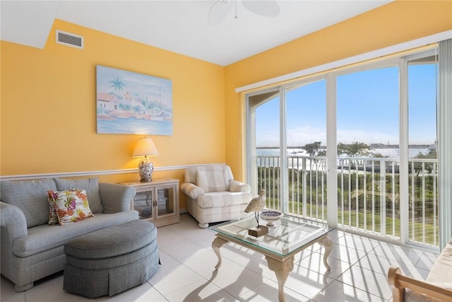 living room featuring a water view, ceiling fan, and light tile patterned flooring