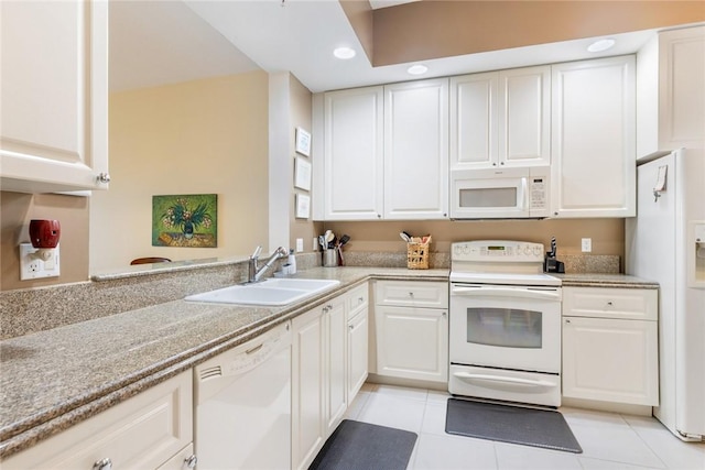 kitchen with light tile patterned flooring, white appliances, sink, white cabinetry, and kitchen peninsula