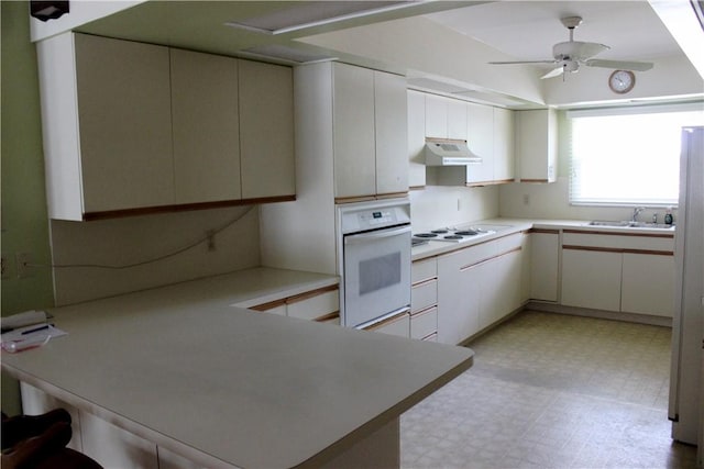 2910 59th Ave, Vero Beach, FL 32966 - kitchen featuring oven, under cabinet range hood, light floors, a peninsula, and ceiling fan