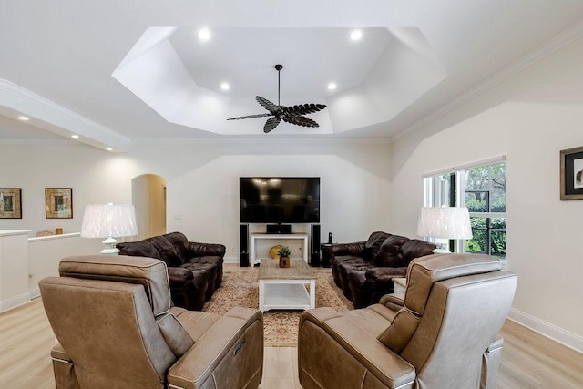 living room with crown molding, light hardwood / wood-style flooring, and a tray ceiling