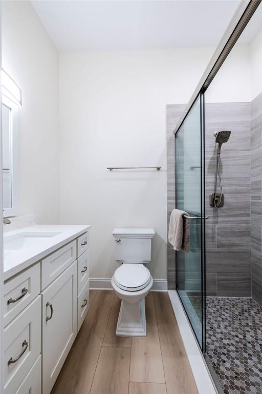 bathroom featuring vanity, hardwood / wood-style floors, toilet, and walk in shower