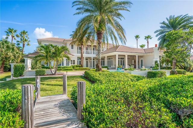 back of house with a lawn and a balcony