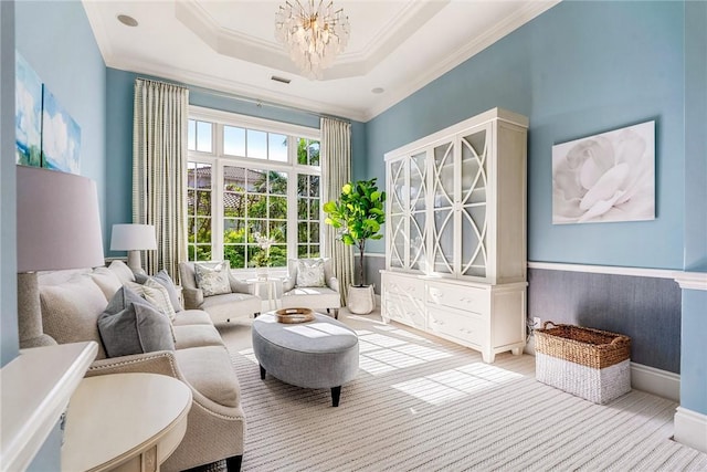 sitting room with a raised ceiling, crown molding, and a notable chandelier