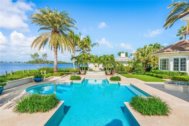 view of swimming pool with a patio area, a water view, and an outdoor fireplace