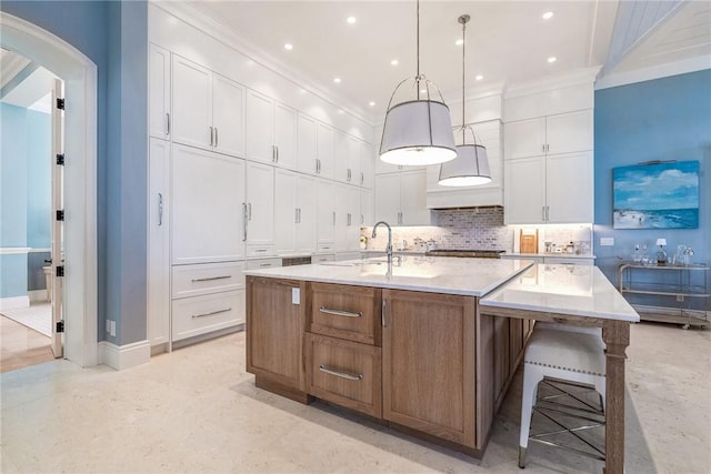 kitchen featuring a large island, crown molding, white cabinets, and hanging light fixtures