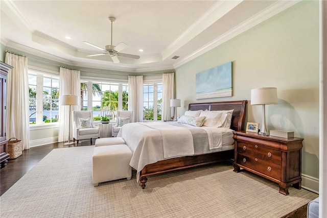 bedroom with ceiling fan, a raised ceiling, wood-type flooring, and crown molding