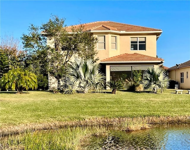 rear view of house featuring a water view and a lawn