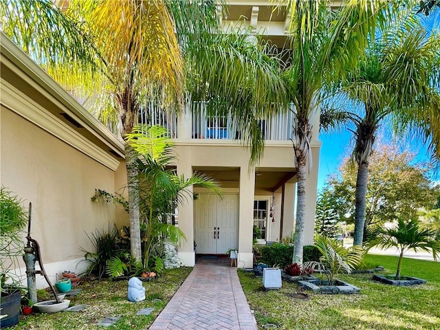 entrance to property featuring a balcony and a lawn